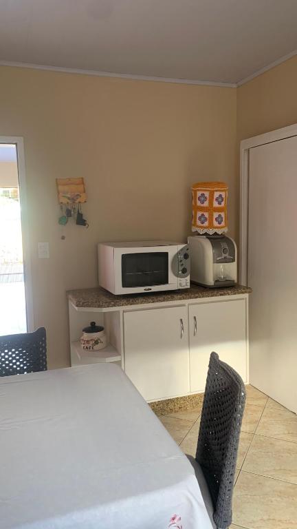 a kitchen with a microwave on a counter with chairs at Casa - Florianópolis, ponta das canas in Florianópolis