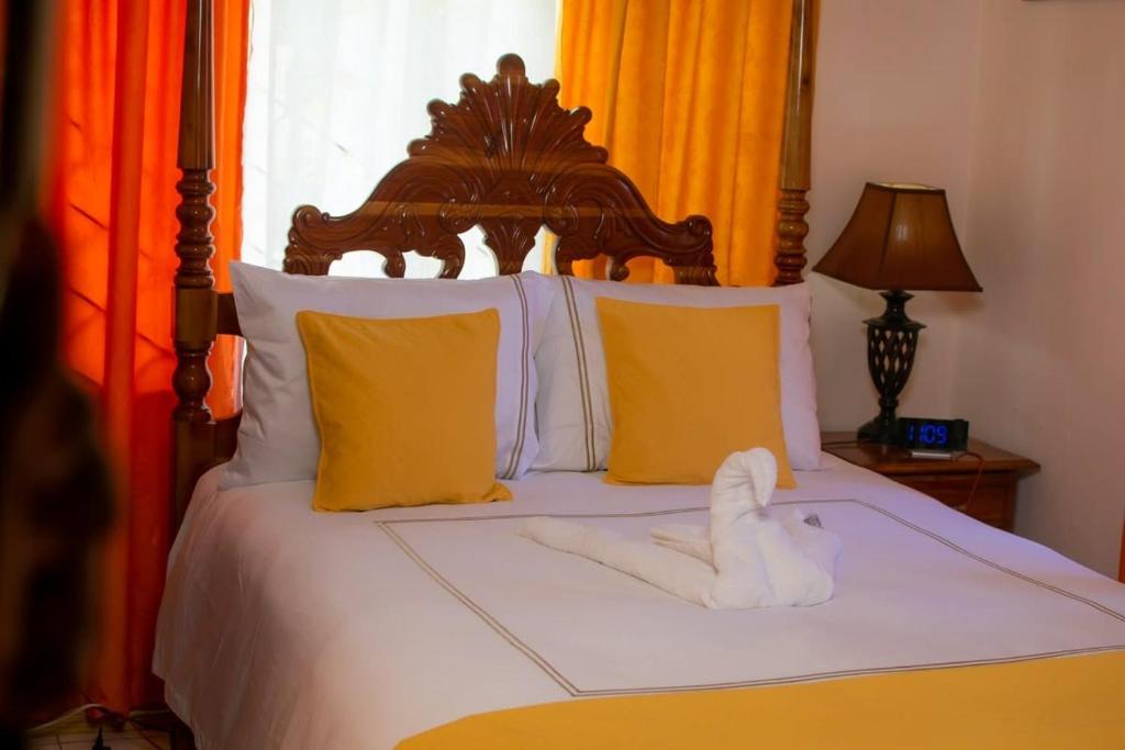 a bed with a wooden headboard and yellow pillows at Windbreak Villa in Buff Bay