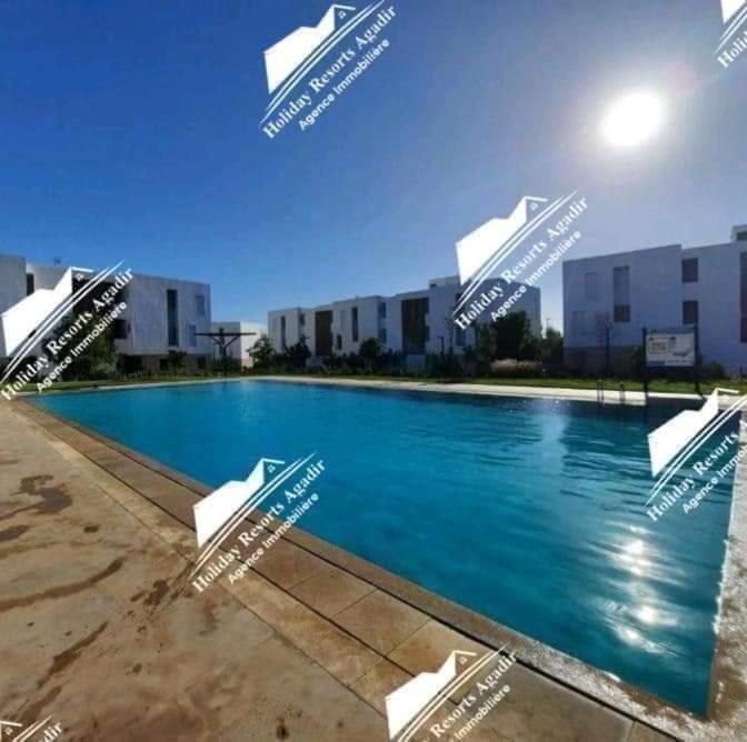 - une piscine avec des chaises en face de certains bâtiments dans l'établissement Ocean 's Whisper 3 Bedroom Taghazout Bay Tamourit, à Taghazout