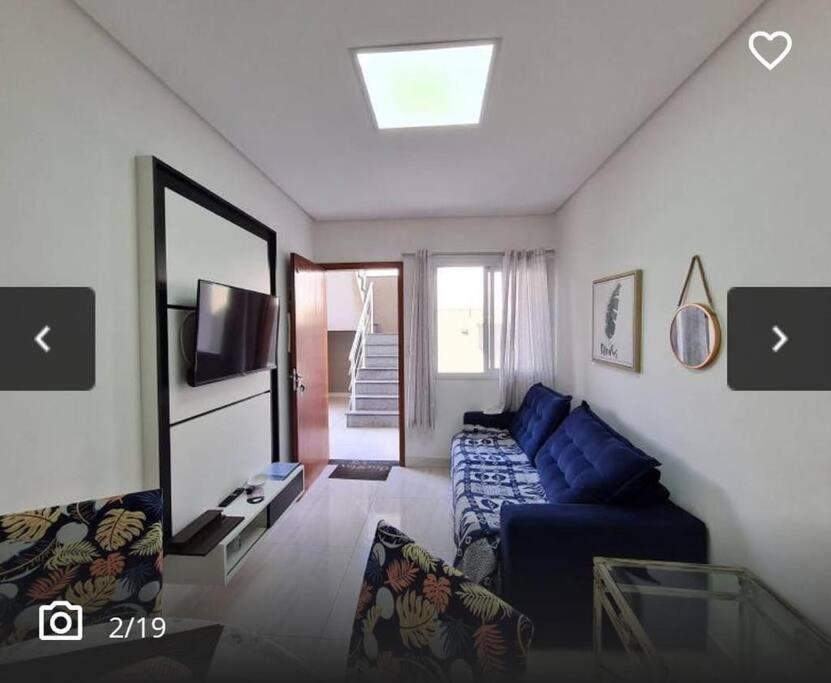 ein Wohnzimmer mit einem blauen Sofa und einem TV in der Unterkunft Apartamento em Vista Linda in Bertioga
