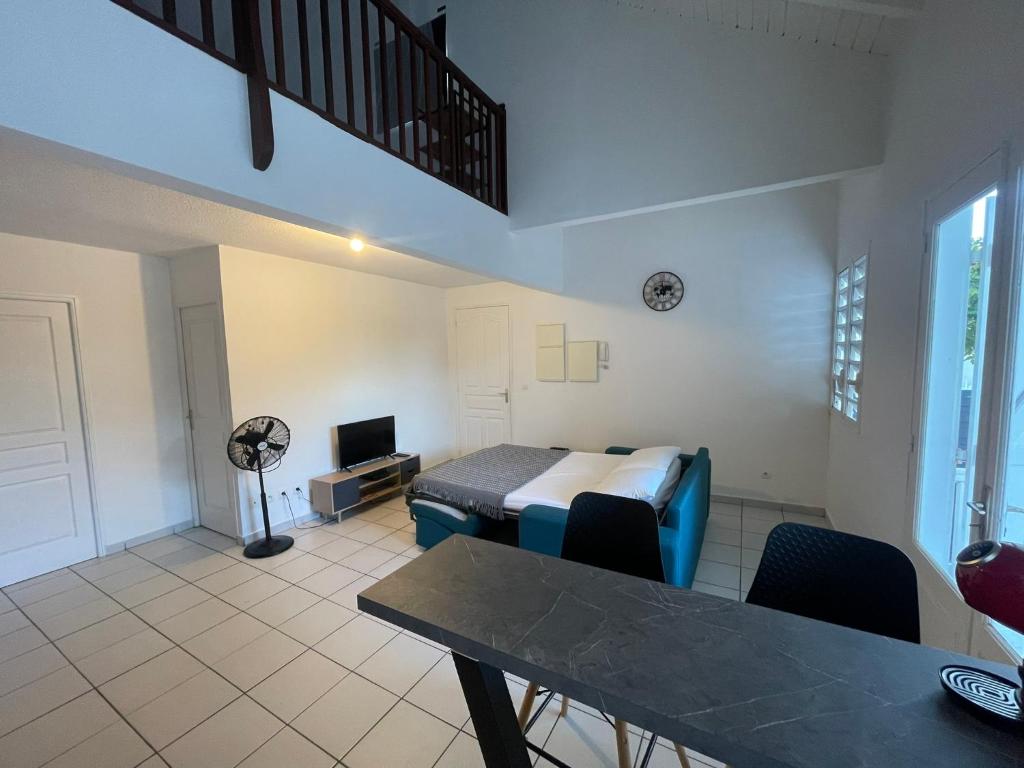 a room with a bed and a table and a tv at Bel appartement cosy - Les pieds dans l'eau in Le Gosier