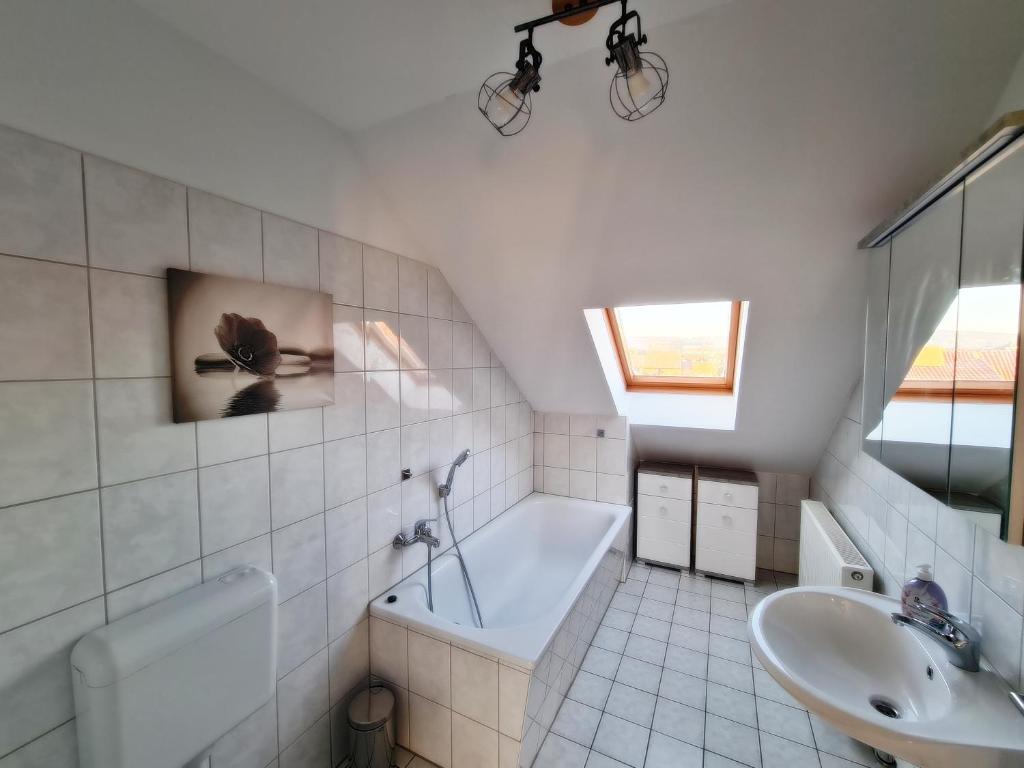 Baño blanco con bañera y lavamanos en DM Hotes & Apartments - Apartment Dosborn 5-9, en Dingelstädt
