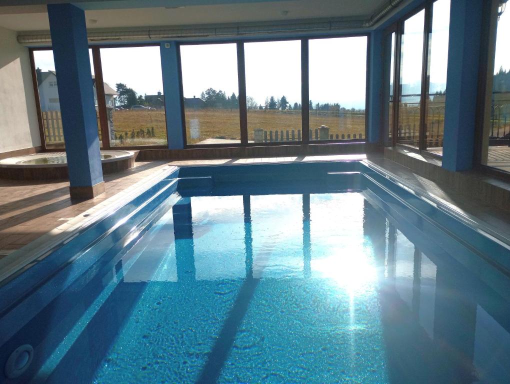 a swimming pool with the sun shining through the windows at Hotel Góralski Raj in Nowy Targ