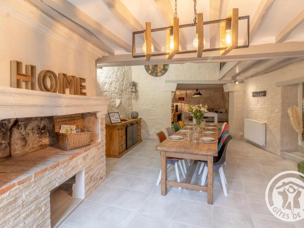 une salle à manger avec une table et une cheminée dans l'établissement Gîte troglodyte unique avec jacuzzi, billard et jardin, près de Doué La Fontaine et Saumur - FR-1-622-69, à Les Ulmes