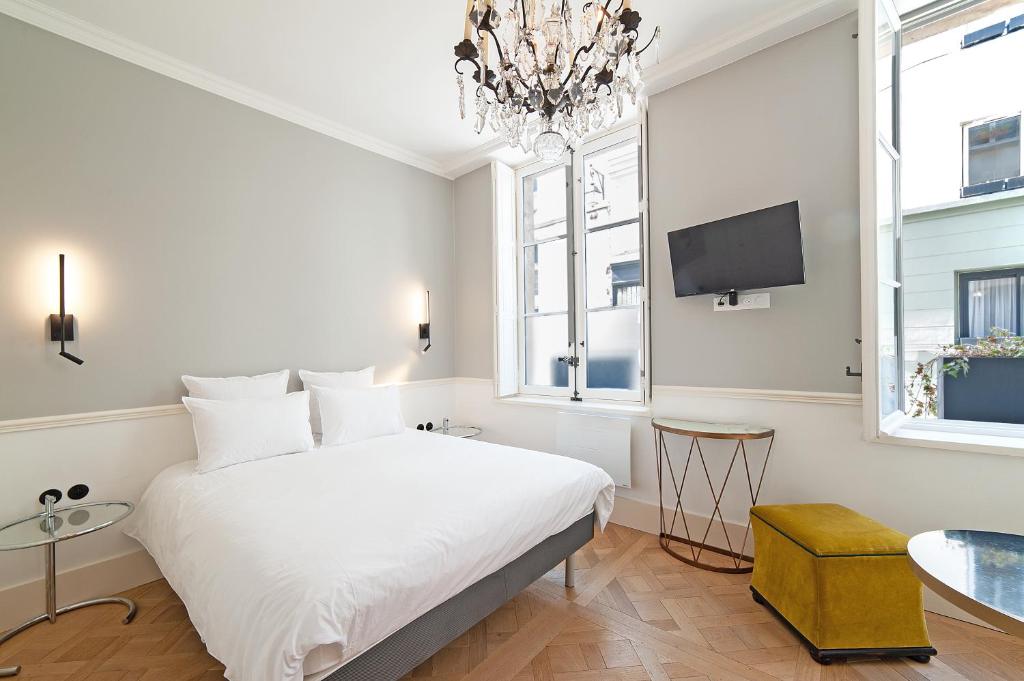 巴黎的住宿－Pavillon Marais，卧室配有白色的床和吊灯。