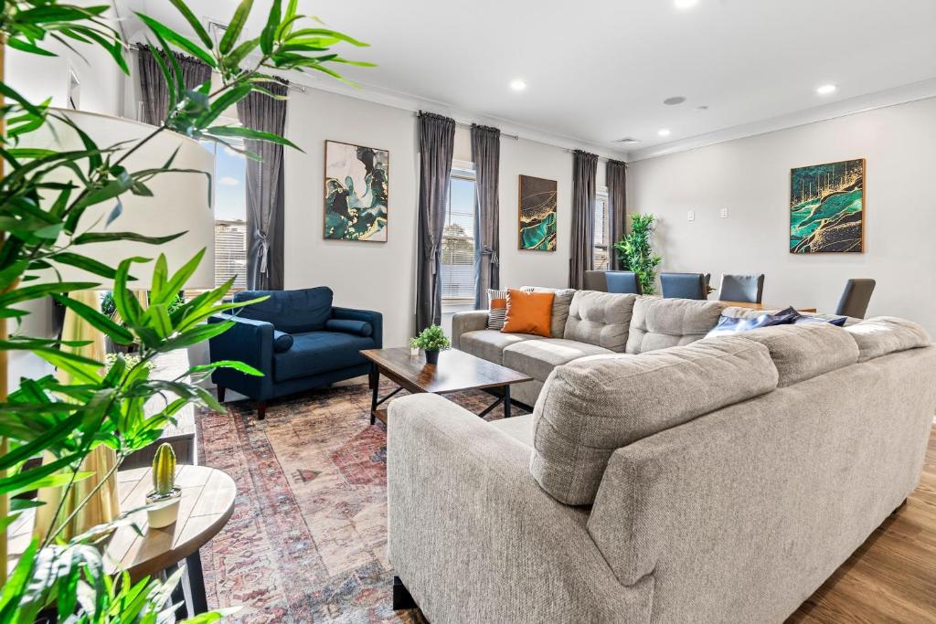 una sala de estar con sofás, mesas y plantas. en Spacious Fully Furnished Apartment by Logan Airport, en Boston