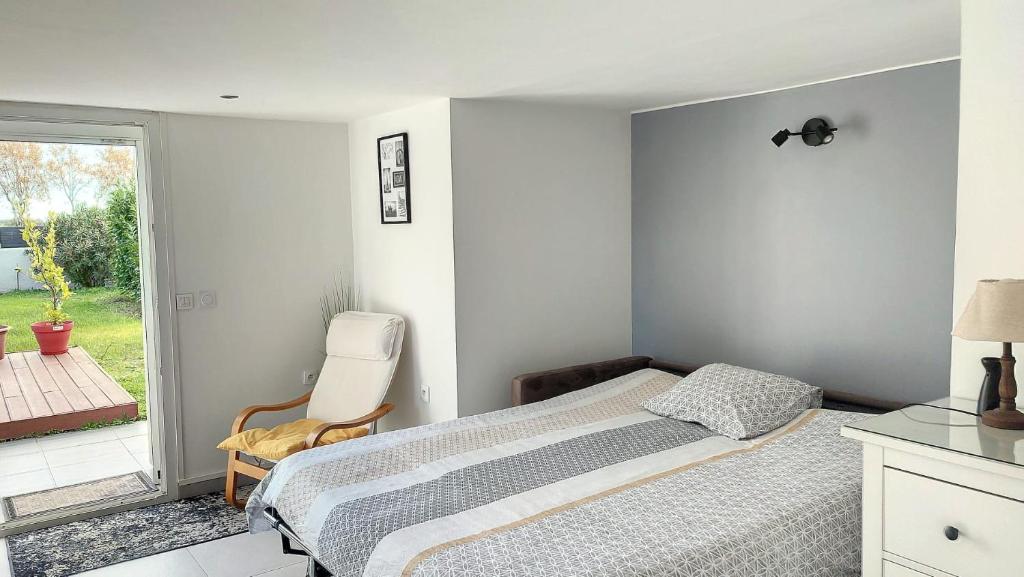 a bedroom with a bed and a chair and a window at Charmant Studio Cosy in Plaisance-du-Touch