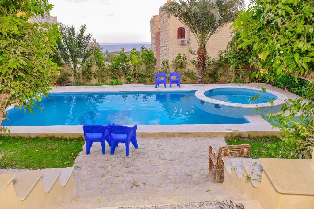 a swimming pool with two blue chairs in front of it at Khan tunis villa in Tunis