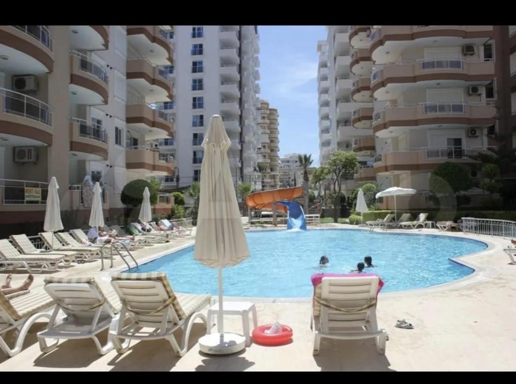 a swimming pool with chairs and umbrellas in a resort at Sokak in Alanya