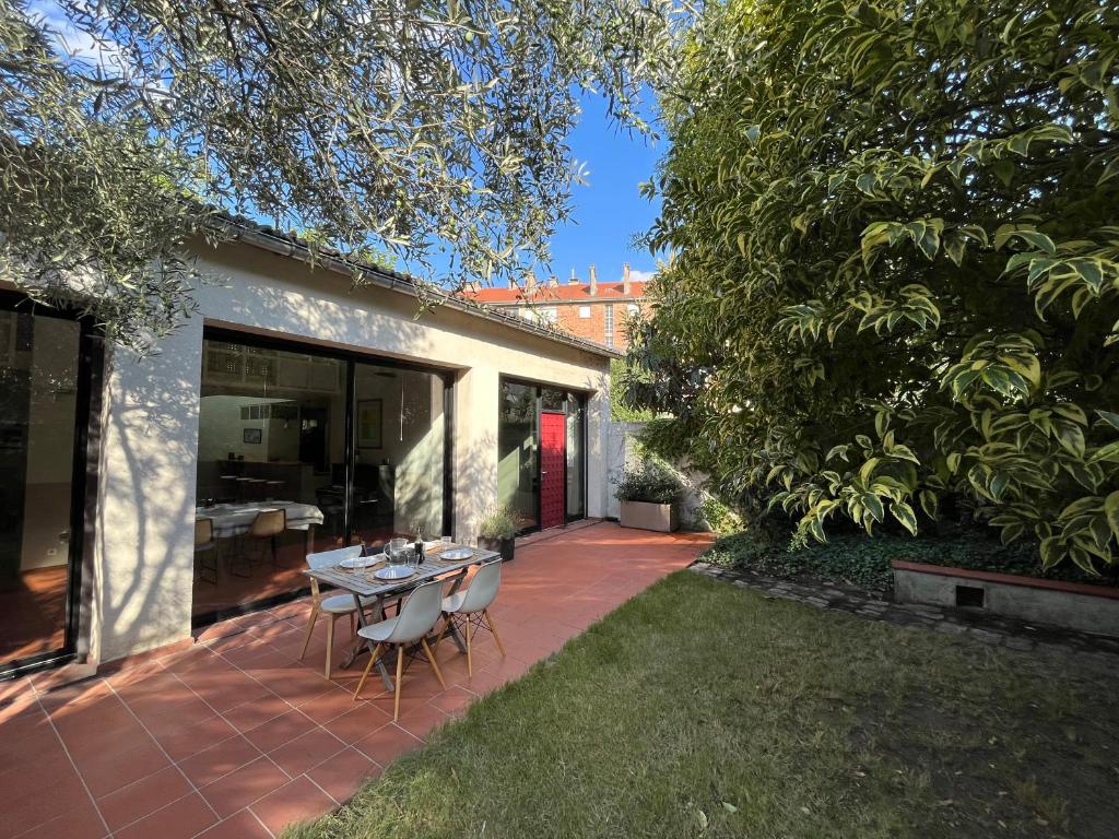 um pátio com uma mesa e cadeiras num quintal em Grande Maison avec jardin et parking proche de Paris em Issy-les-Moulineaux