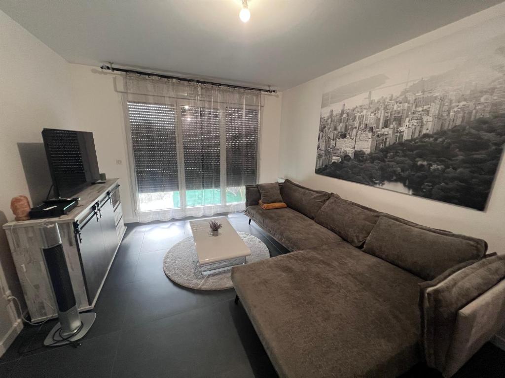 a living room with a couch and a television at Appartement proche Paris, C DG, Disney, Parking. in Aulnay-sous-Bois
