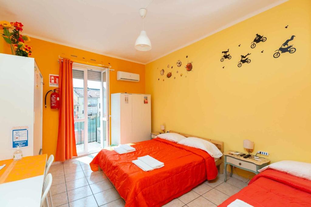 sypialnia z 2 łóżkami i pomarańczowymi ścianami w obiekcie Grotta dello Sport w Turynie