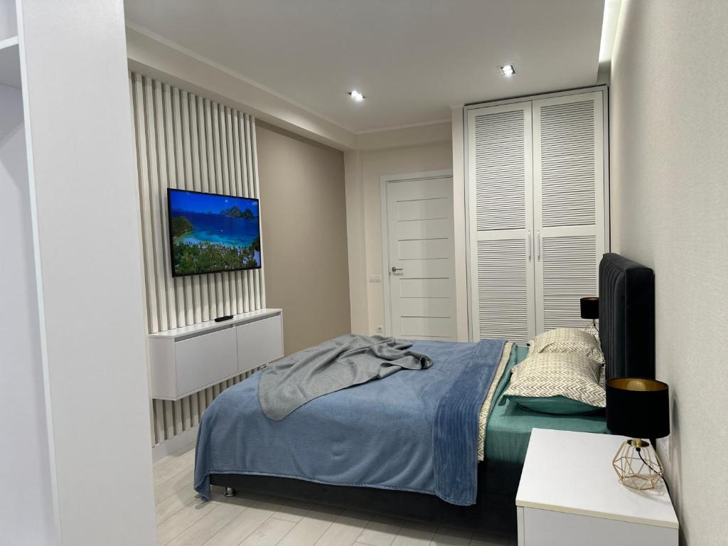 a bedroom with a bed and a flat screen tv at MODERN MINIMALIST APARTMENT Close to Airport and City Center. in Chişinău