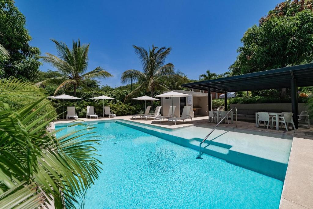 una piscina con mesas, sillas y sombrillas en 3017 - Agaves 104, en Santa Cruz Huatulco