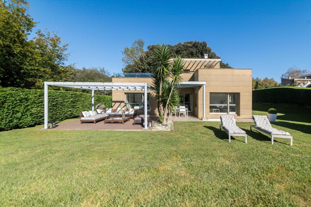 a backyard with two chairs and a pergola at helloasturias, Casa en Llanes con piscina, jardín, cerca de la playa. in Llanes