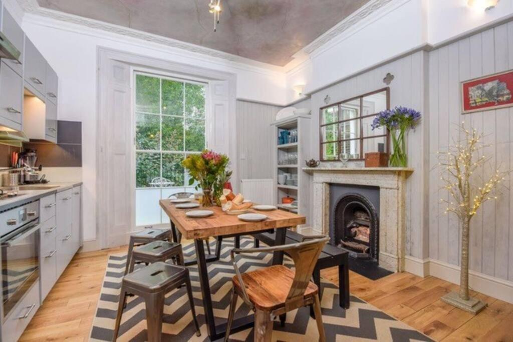 a kitchen with a wooden table and a fireplace at Spacious 4 bed, Central Camden in London