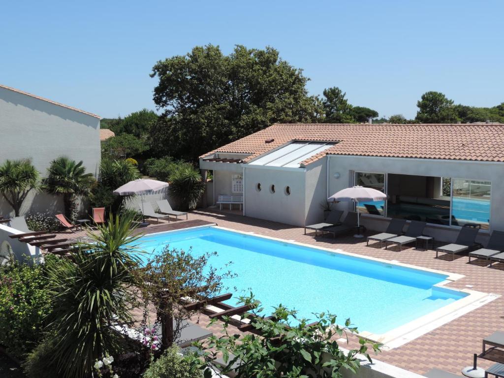eine Villa mit einem Pool und einem Haus in der Unterkunft Hotel L'Oceane in La Cotinière