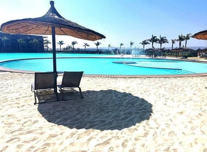 two chairs and an umbrella on the beach at The blyde-Luxury one bedroom apartment in Pretoria