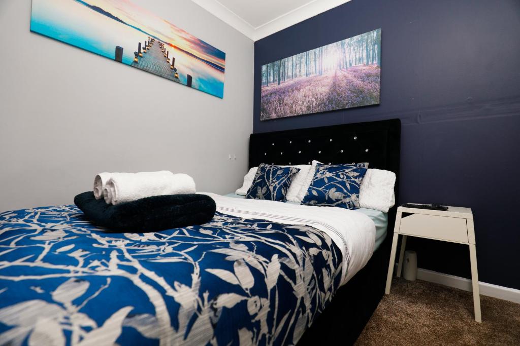 Schlafzimmer mit einem blauen und weißen Bett und einem Tisch in der Unterkunft Harmony Haven - Ocean Drive Suite in Nottingham