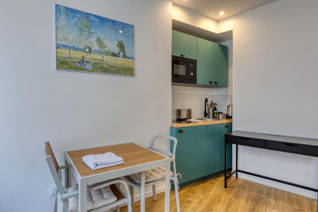 una pequeña cocina con una mesa pequeña, una mesa y sillas en Les Vignes de Montmartre - Studio, en París