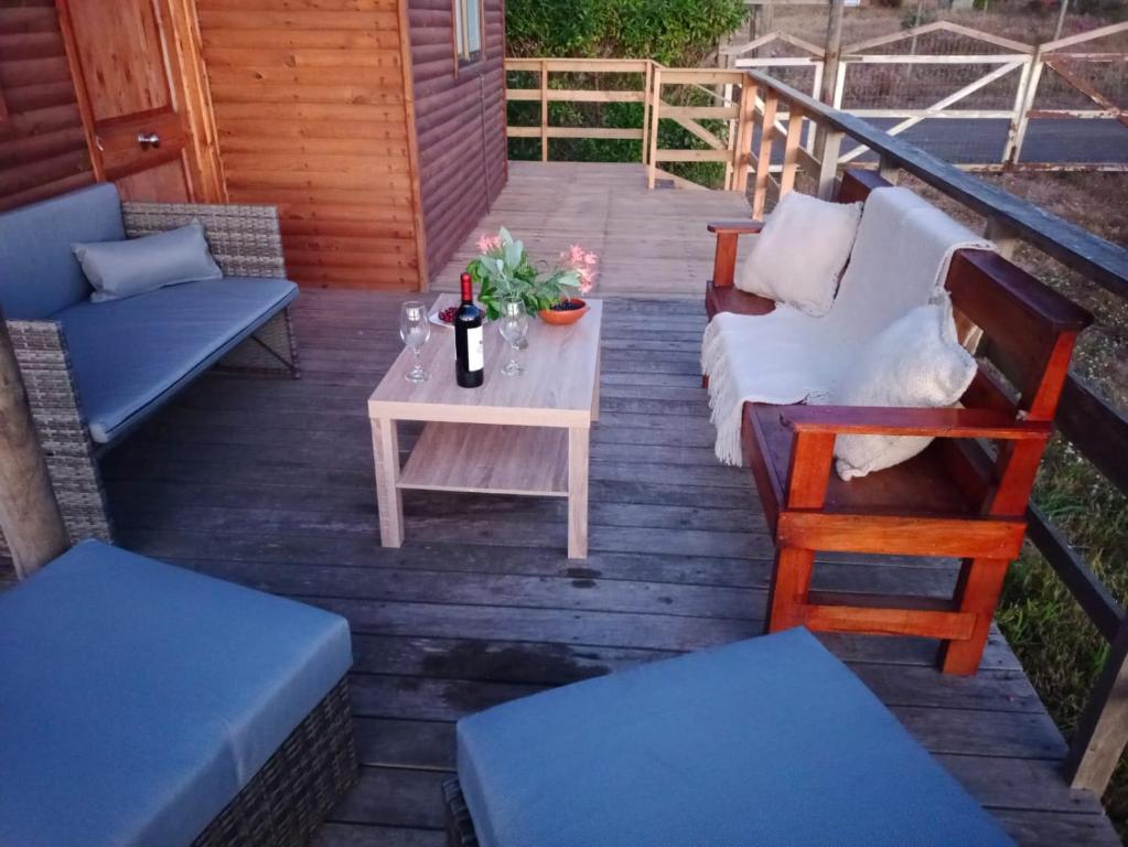 un patio con sofá y una mesa con una botella de vino en Acun Lihuen, en Cobquecura