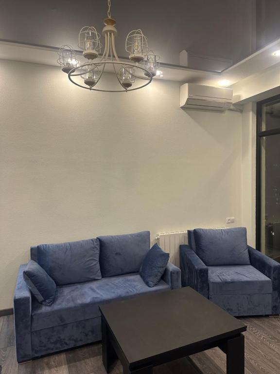 a living room with a blue couch and a table at Jikia Residence in Tbilisi City