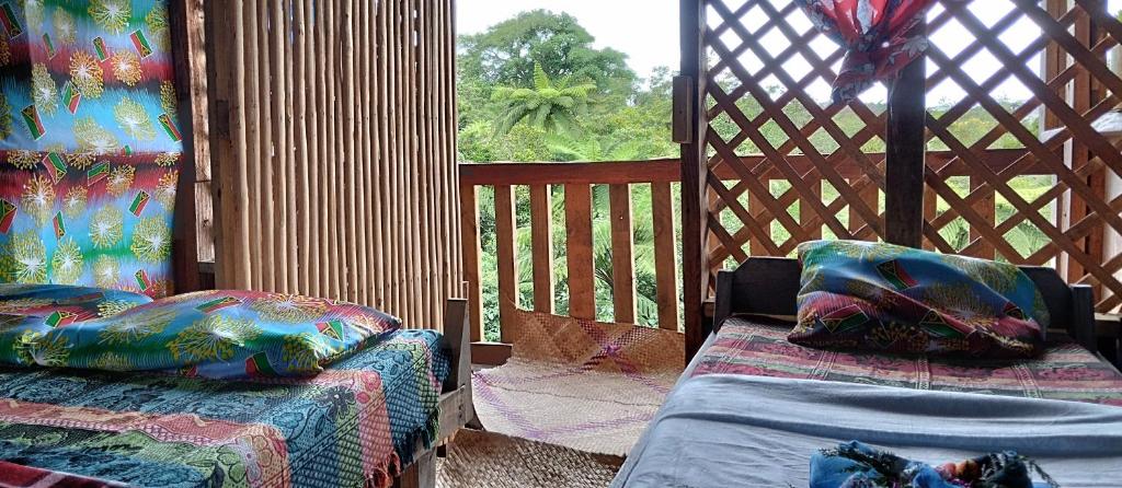 a gazebo with two beds and a window at Glowing Mountain view tree house in Loanengo