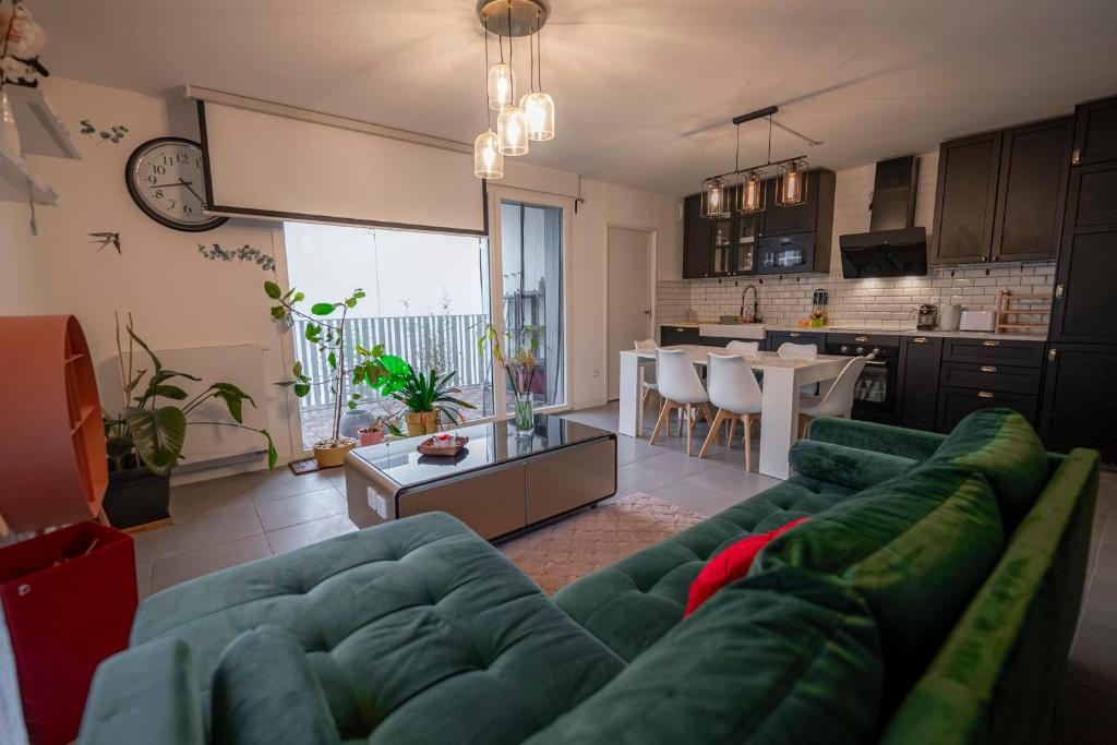 a living room with a green couch and a kitchen at Spacious apartment near the beach in Bordeaux