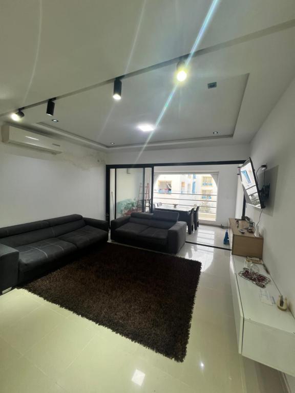 a living room with a black couch and a tv at Appartement marina hammamet in Hammamet