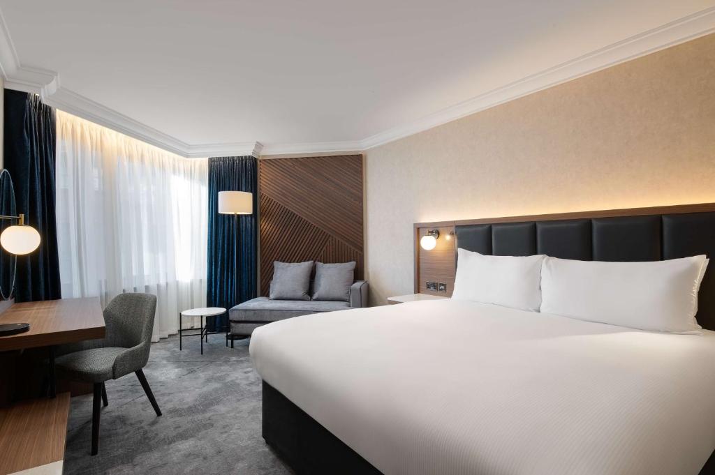 a hotel room with a large bed and a desk at Hilton London Metropole in London