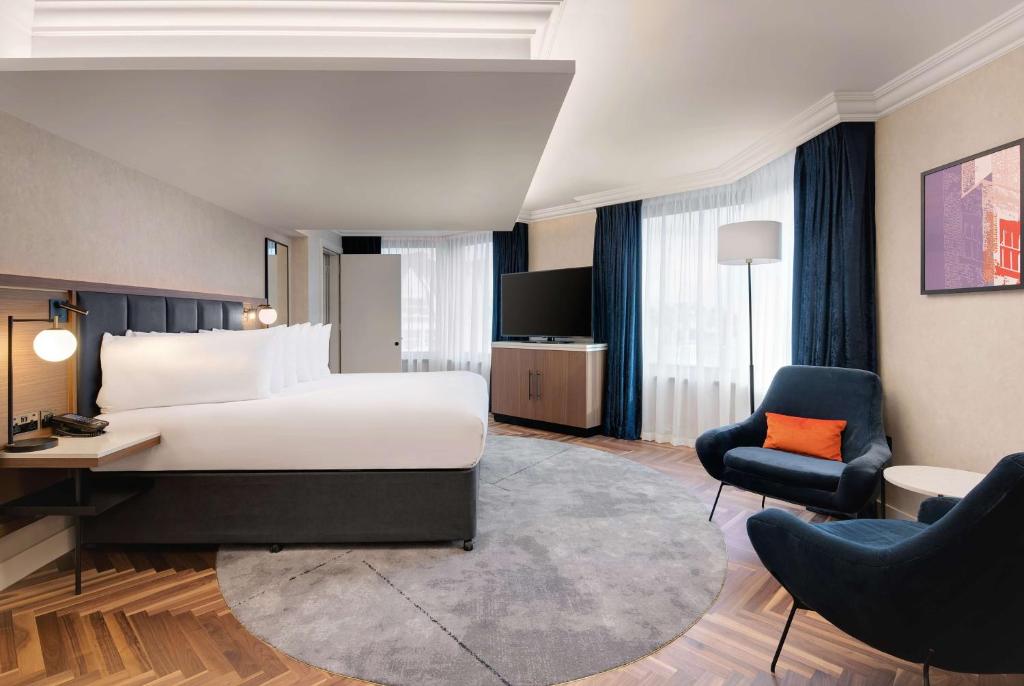 a hotel room with a bed and a desk and a chair at Hilton London Metropole in London
