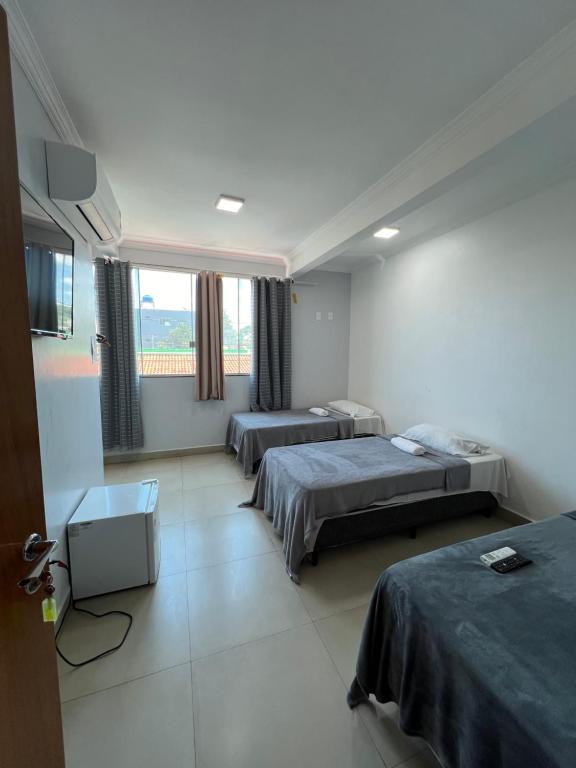 a hotel room with two beds and a window at Hotel Brasília - centro in Brasilia