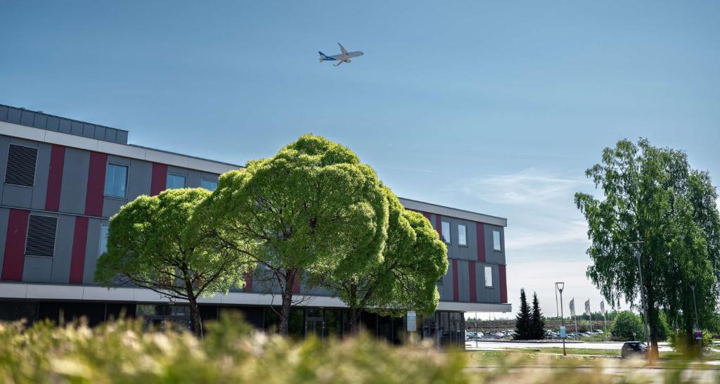 a tree in front of a building with a plane at Best Western Plus Oslo Airport in Gardermoen