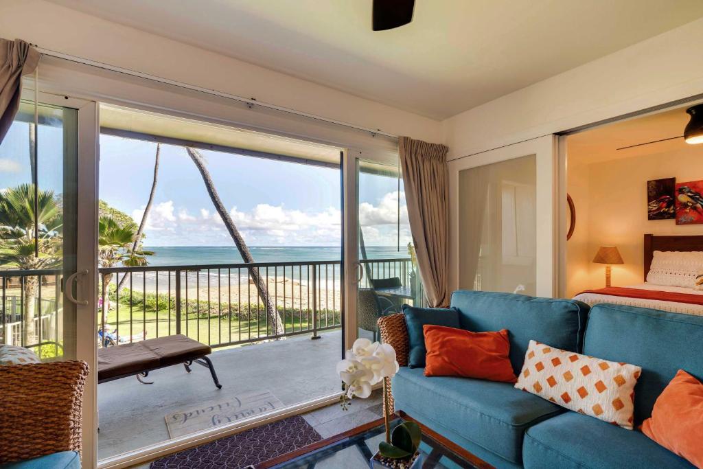 Waipouli Beachfront Condo with Balcony and Ocean Views في كابا: غرفة معيشة مع أريكة زرقاء وإطلالة على المحيط