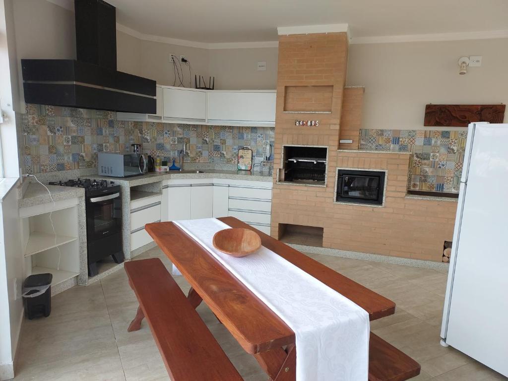 a kitchen with a wooden table and a refrigerator at Alto Padrão! Vista linda! Churrasqueira! Hidro! in Poços de Caldas