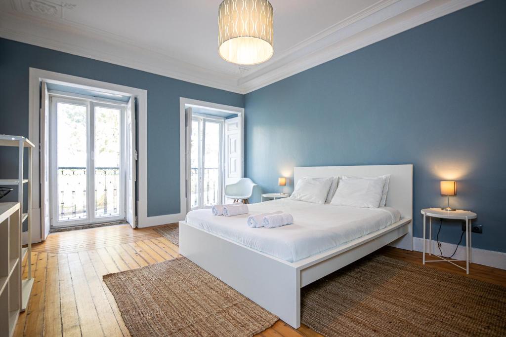 a bedroom with a large white bed with blue walls at VAGO Alcântara Suites in Lisbon
