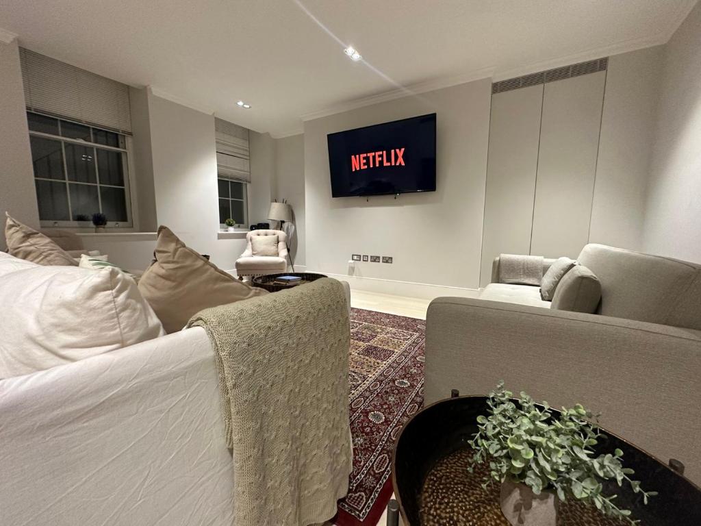 een woonkamer met een televisie aan de muur bij Chic Covent Garden Apartment By Sloanes Group in Londen