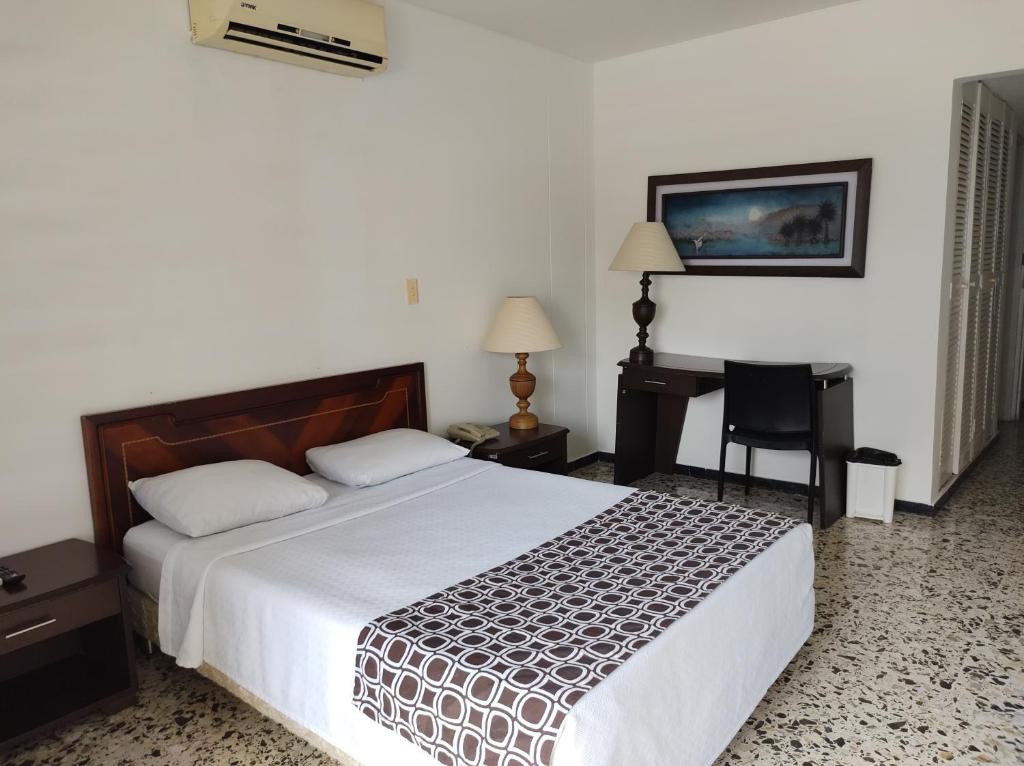 a bedroom with a large bed and a desk at Hotel Estación by Destino Pacifico in Buenaventura