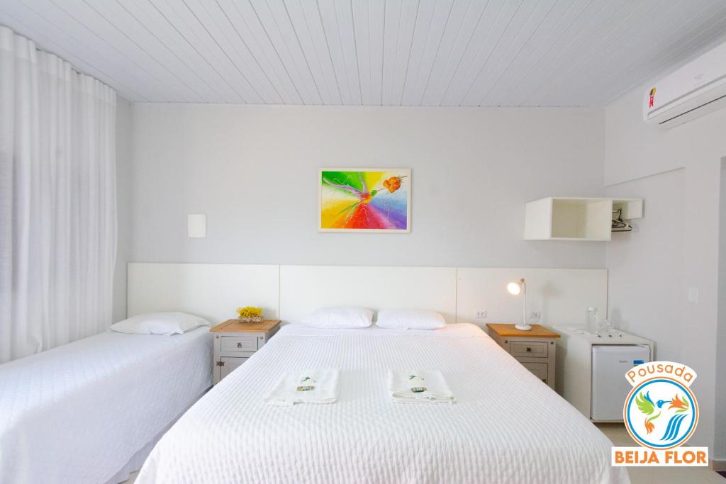a bedroom with two beds and a painting on the wall at Pousada Beija-Flor in Chapada dos Guimarães