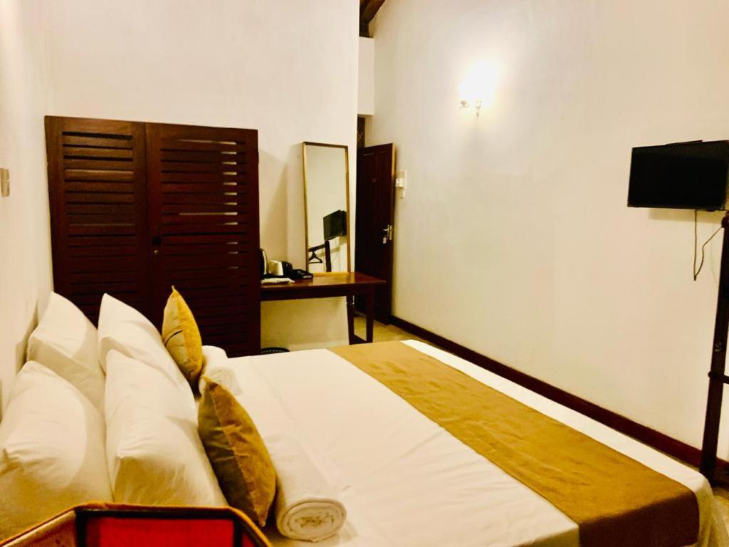 a bedroom with a bed and a television in it at Salty Seahorse Mount Lavinia in Watumulla