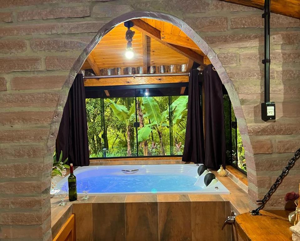La salle de bains est pourvue d'une fenêtre cintrée et d'une baignoire. dans l'établissement Aldeia Pé da Serra Cabana Natureza, à Três Coroas