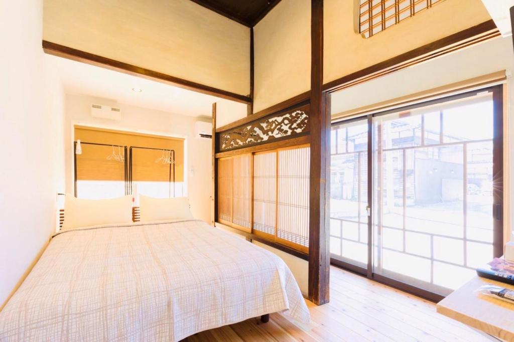a bedroom with a bed and a large window at FARMSTAY miyuki-street "Goen" in Ukiha