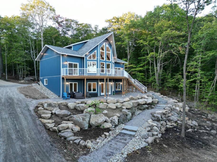 a blue house in the middle of a road at Luxury Waterfront Cottage on Little Doe Lake in Burks Falls