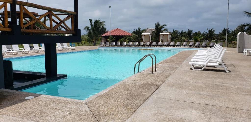 einen Pool mit weißen Liegestühlen in einem Resort in der Unterkunft PUNTA COCO VILLAS BEACH in Cojimíes