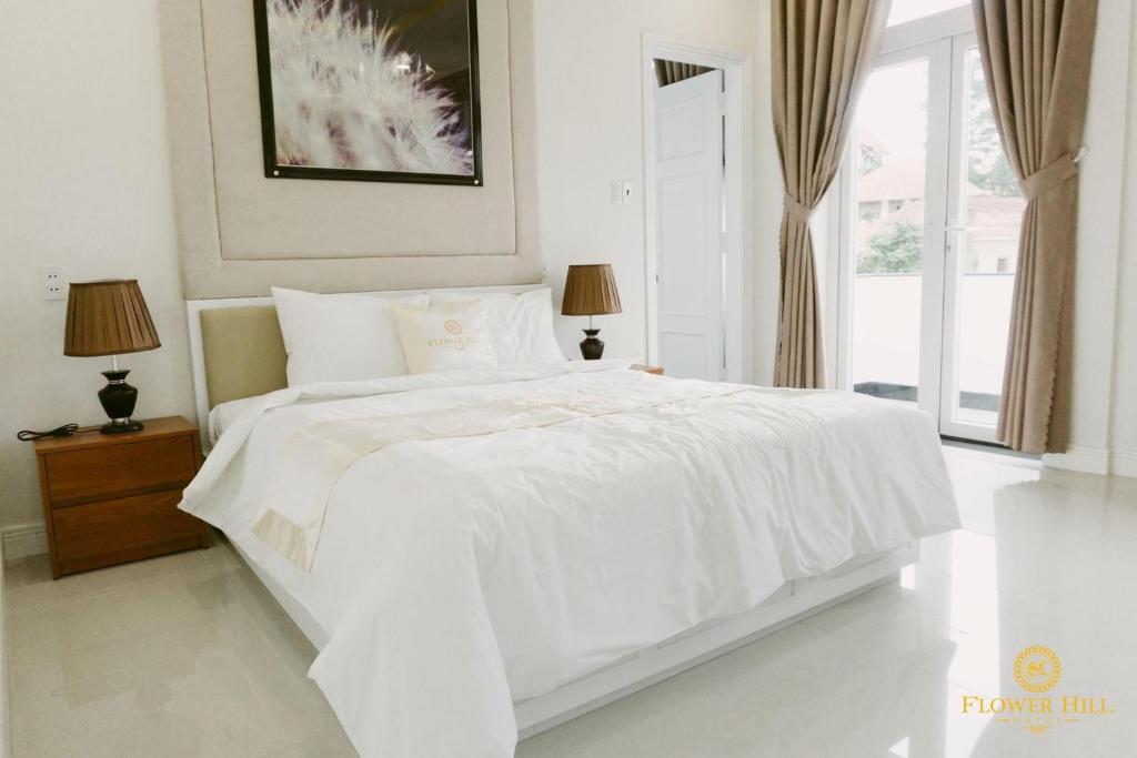 a white bedroom with a white bed and a window at Flower Hill in Da Lat