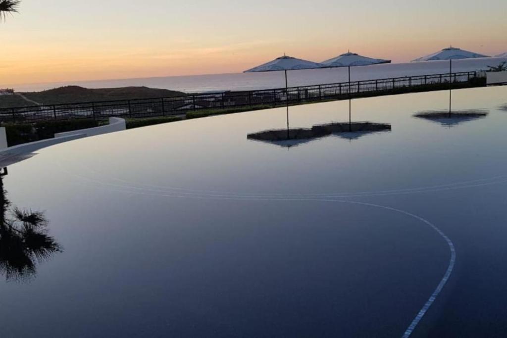 uma grande piscina com guarda-sóis numa praia em Exquisite 3BR Condo Ocean Views Access Resorts em Cabo San Lucas