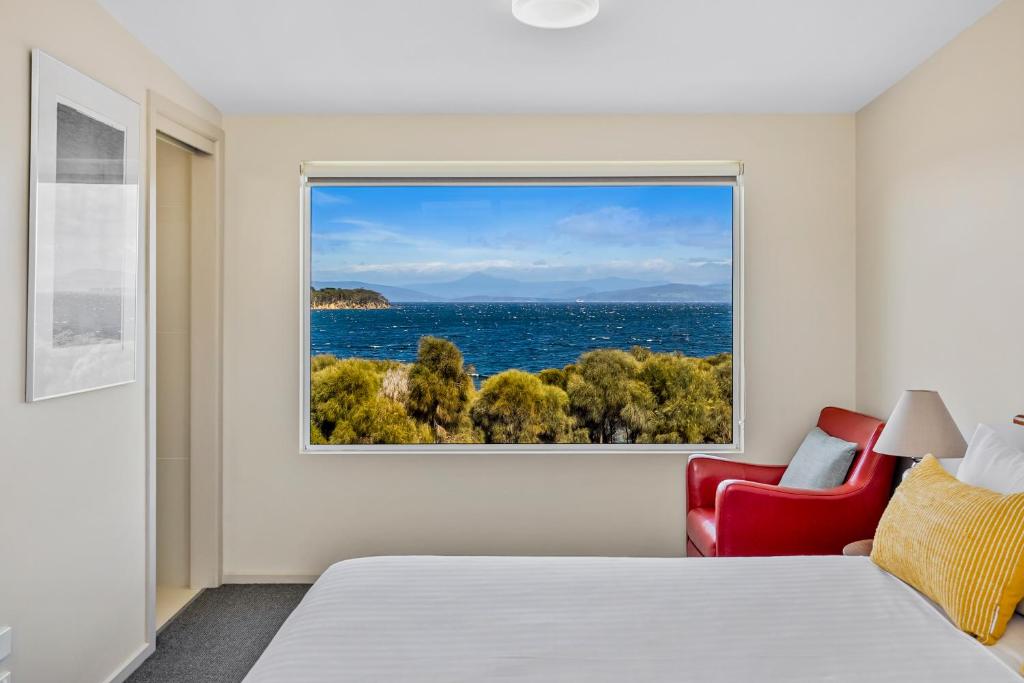 a bedroom with a window with a view of the ocean at Manfield Seaside Bruny Island in Alonnah