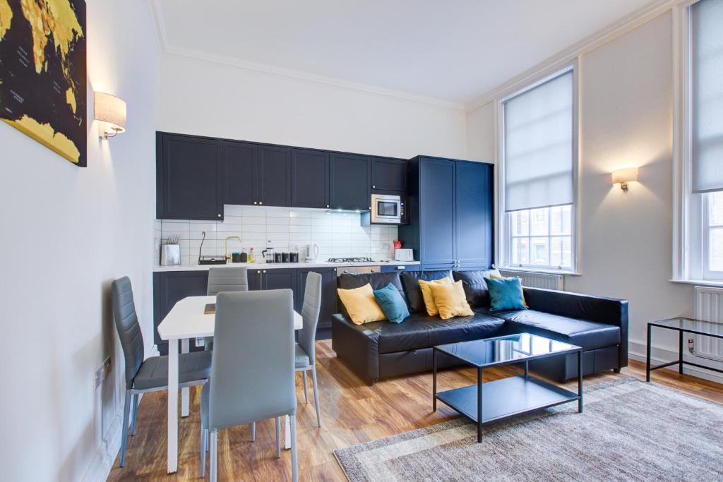 a living room with a black couch and a kitchen at London Central in London