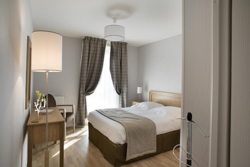 1 dormitorio con cama, escritorio y ventana en Domitys La Clef des Champs, en Poitiers