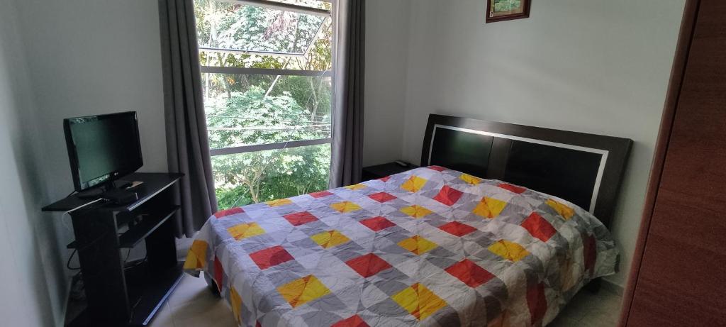 ein Schlafzimmer mit einer Decke auf einem Bett und einem Fenster in der Unterkunft Apartaestudio cerca al parque principal in Los Andes
